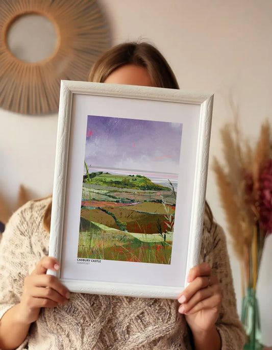 Cadbury Castle art print by Vicki Shortt, the wooded Iron Age hillfort rising above layered Somerset fields, framed and held up in a room setting